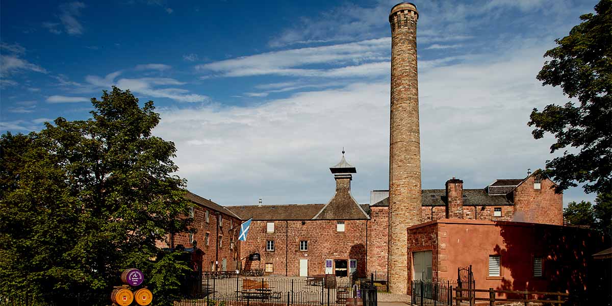 Annandale Distillery exterior. A large chimney rises up into the blue sky from the distillery.