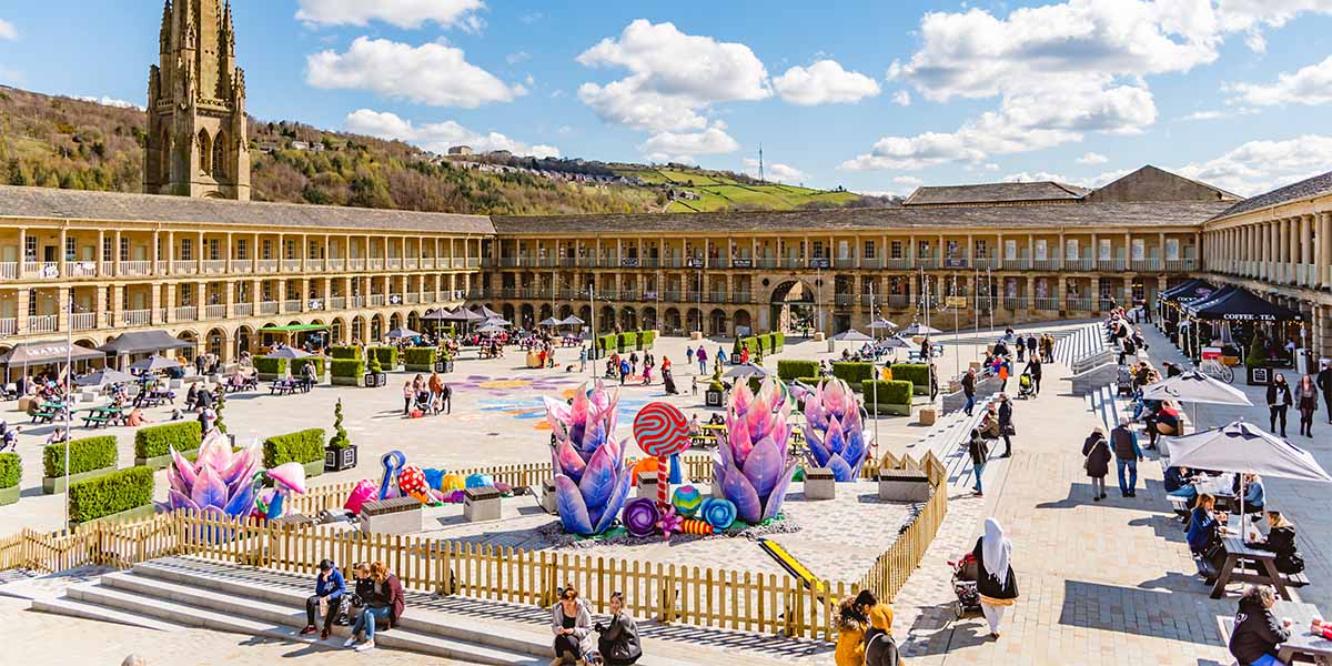 People sit outside the The Piece Hall, in Halifax, West Yorkshire, in beautiful weather, enjoying the sights and sounds of the market