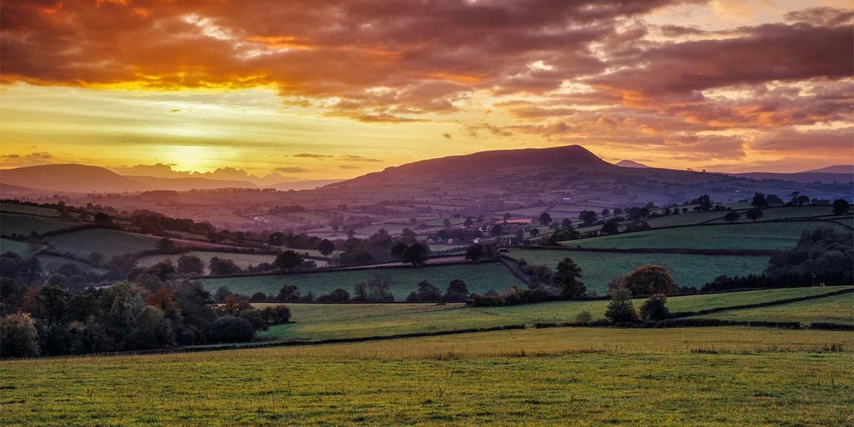 The sun setting behind a mountain in Monmouthshire, Wales